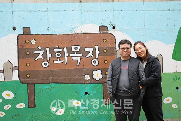 지준식 창화농장 대표와 아내 고선명 씨가 농장 벽화 앞에서 함께 포즈를 취하고 있다.
