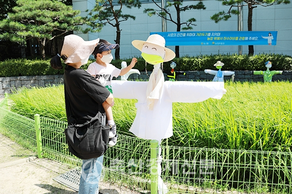 한 시민이 아이와 함께 서울시 중구 농업박물관 야외체험장에 설치된 허수아비를 관람하고 있다.