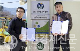 박건용 산수유 양돈교육농장 대표(오른쪽)와 서만형 엠트리센 대표가 업무협약을 체결 후 양돈장 앞에서 기념촬영을 하고 있다.